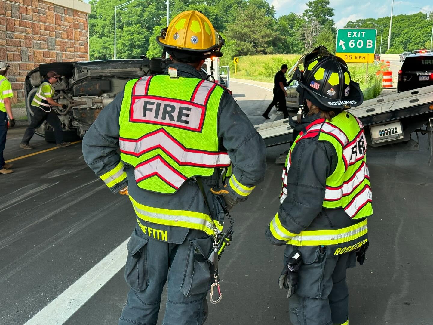 two fire fighters in neon safety gear assessing damage from car crash